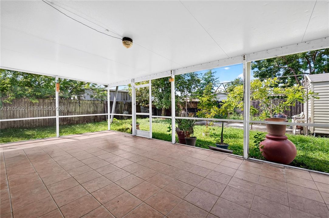 Screened-in covered patio featuring tile flooring, a solid ceiling, and a full-height screen enclosure