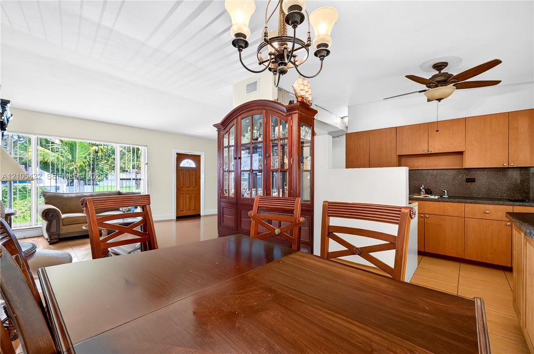 Kitchen featuring wood cabinetry, stone countertops, tile flooring, a multi-arm chandelier, and a ceiling fan