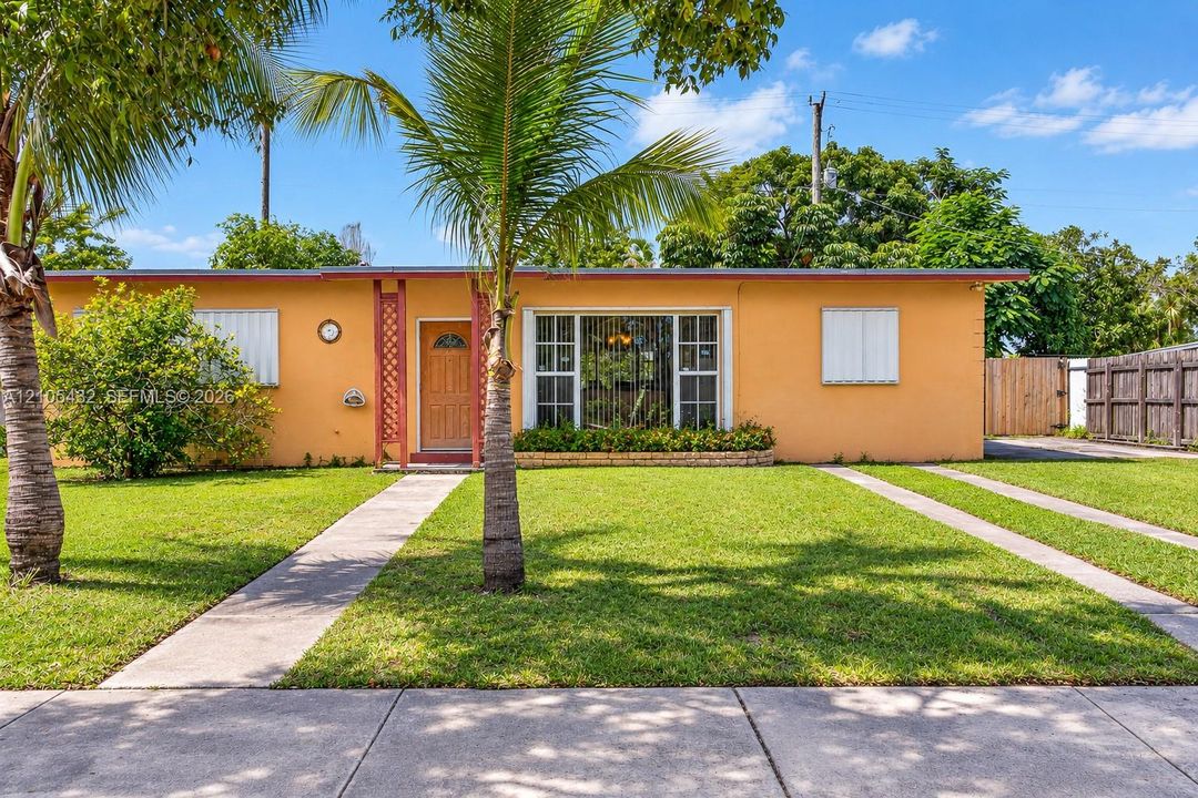 Single-story exterior featuring a stucco facade, large picture window with a masonry planter, wood-finish entry door, and a concrete ribbon driveway