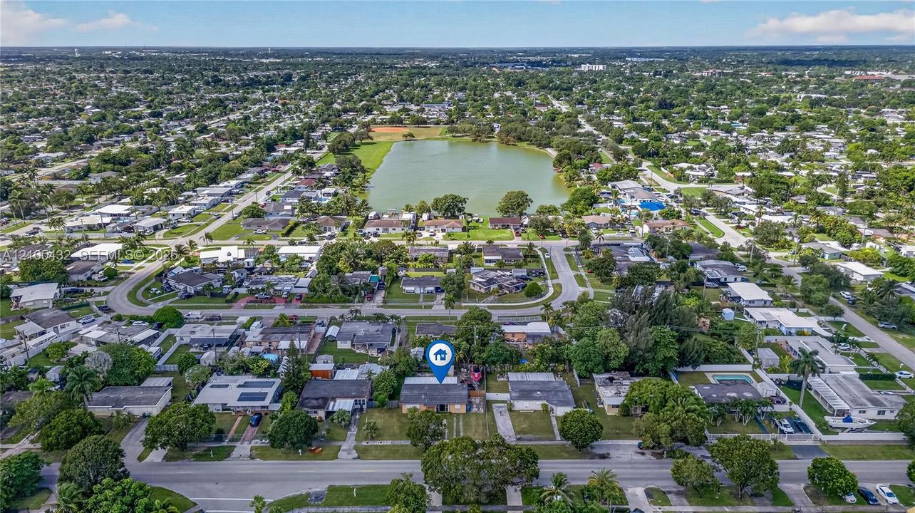 Aerial perspective featuring a low-density residential neighborhood with mature landscaping and proximity to a central community lake