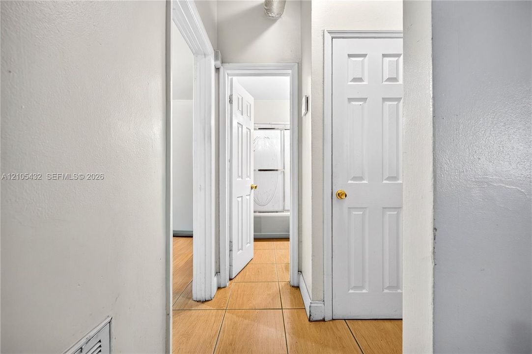 Hallway featuring wood-finish tile flooring, white six-panel interior doors, and door casings