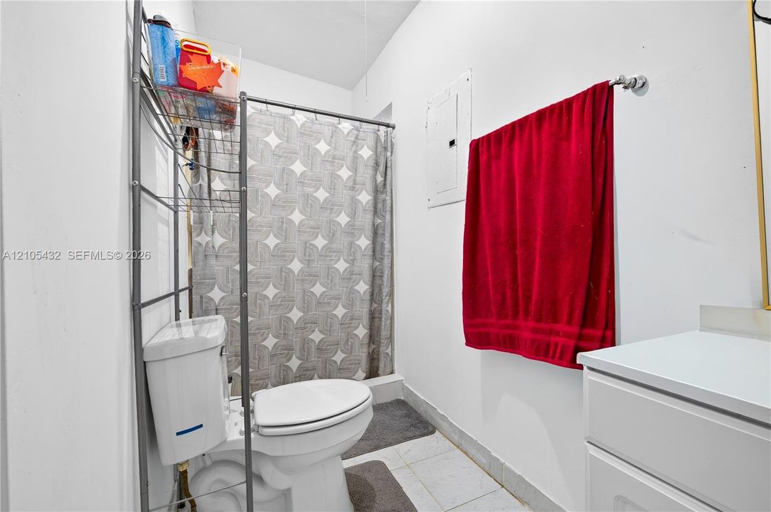 Bathroom featuring a white vanity cabinet, a wall-mounted electrical panel, and a tile floor