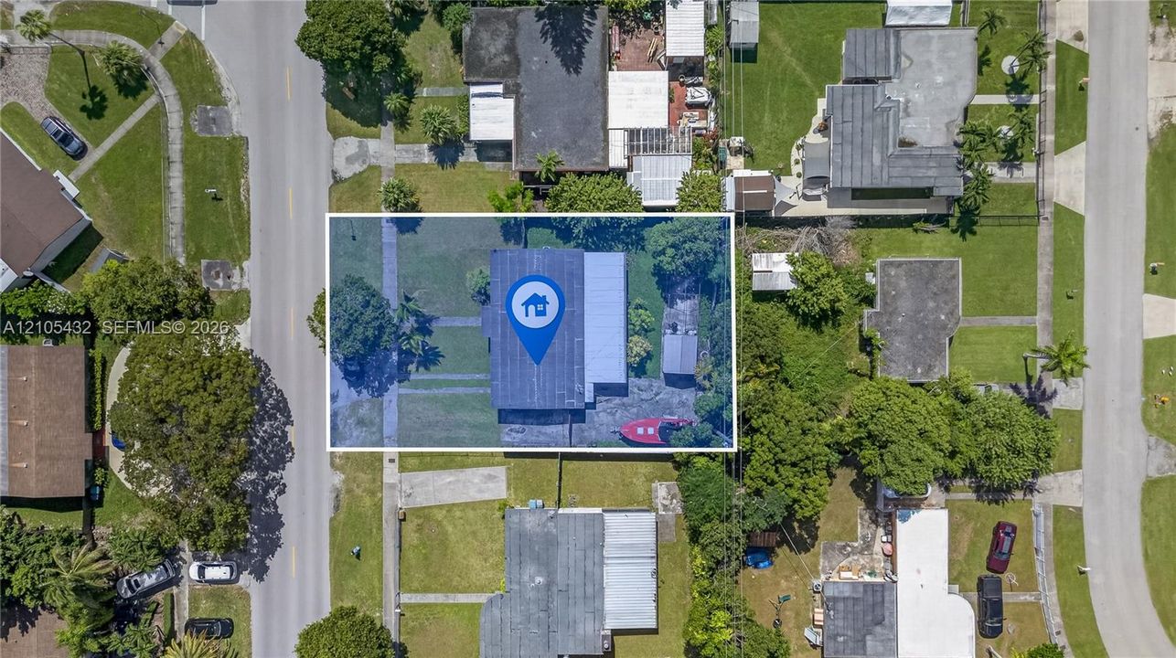 Aerial perspective of a rectangular lot featuring a residence with a flat roof, an attached side structure, and mature vegetation