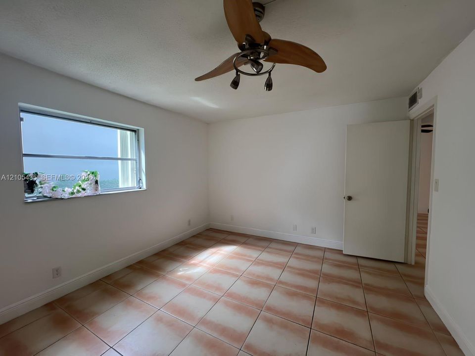 Interior room featuring neutral wall finishes, tile flooring, a multi-pane horizontal window, and a ceiling fan with integrated lighting