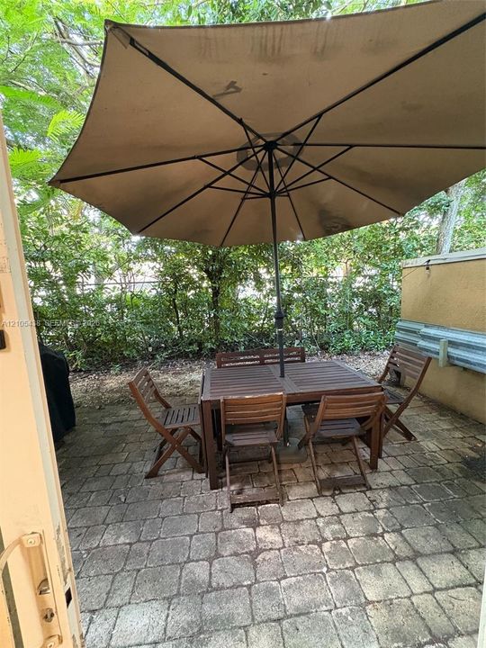 Stone paver patio featuring a perimeter of mature foliage