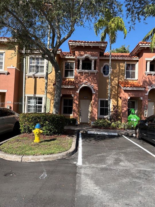 Mediterranean-style exterior featuring a clay tile roof, arched entryway, decorative stucco detailing, and multi-pane windows