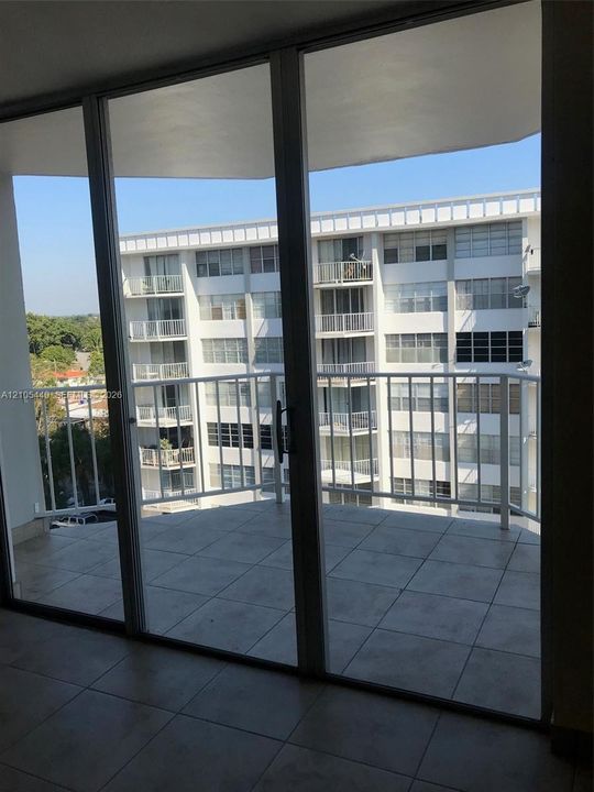 Expansive balcony with tile flooring and white metal railing, accessed through large sliding glass doors