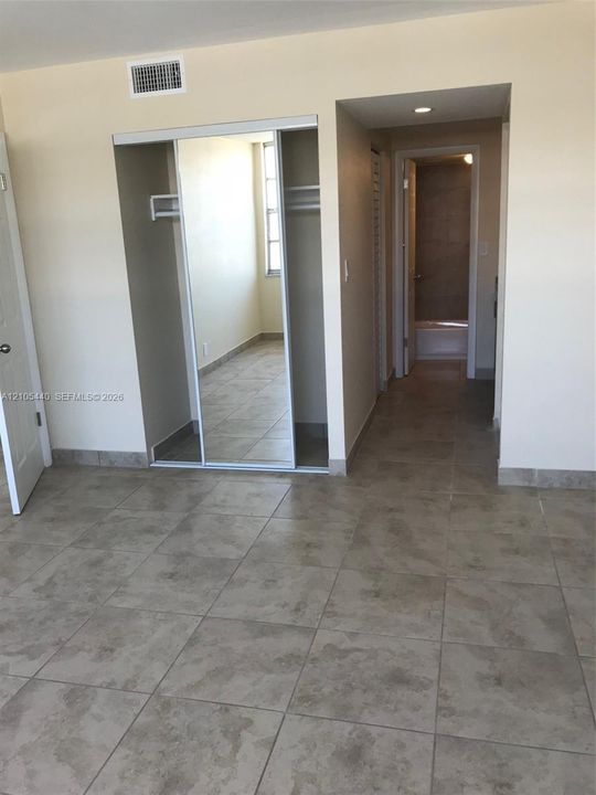 Tile flooring with a neutral finish, mirrored closet doors, and recessed lighting