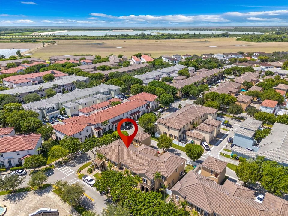 Aerial perspective of a multi-story residential complex featuring tile roofing and paved driveways situated within a planned community