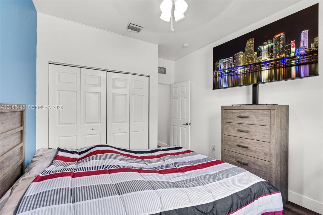 Bedroom featuring white paneled closet doors, high ceilings, ceiling fan with light fixture, and six-panel interior doors