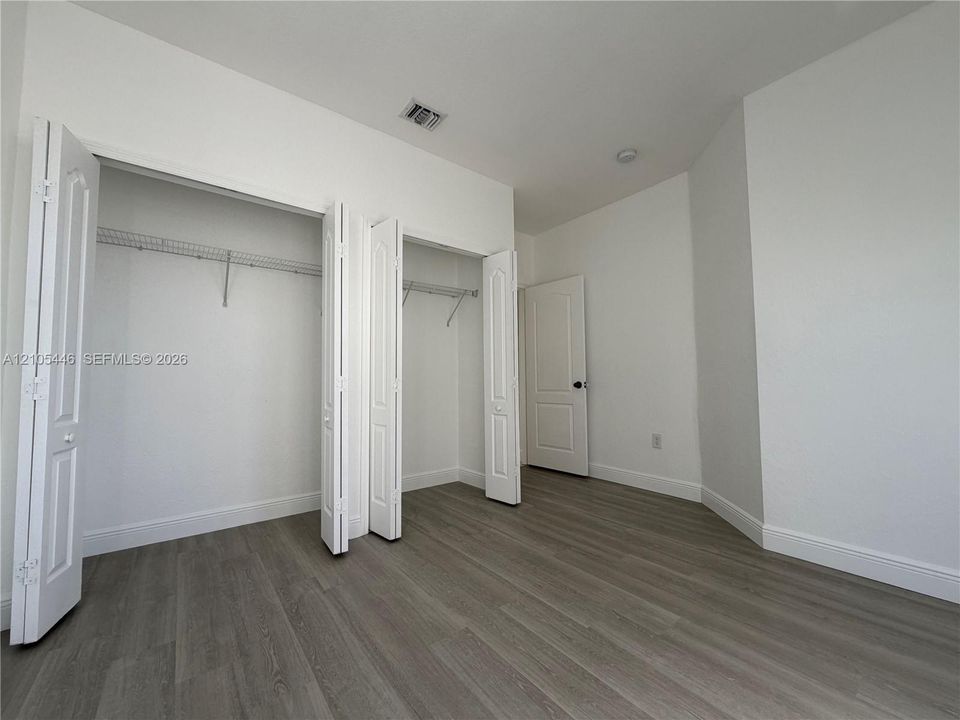Wood-finish flooring, white walls, bi-fold closet doors, wire shelving, and a recessed ceiling light