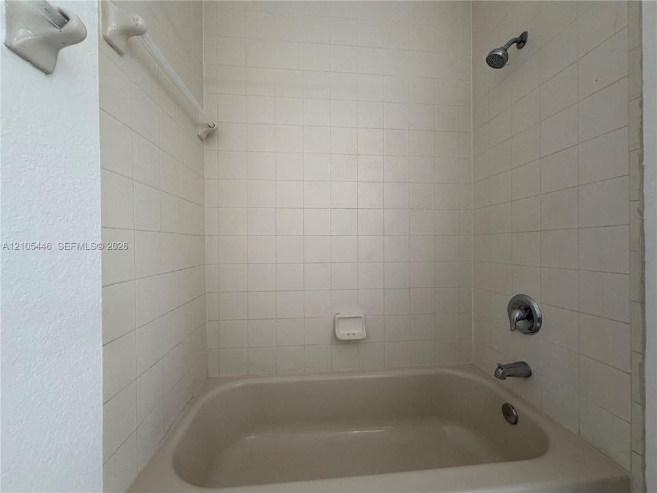 Bathtub with tiled surround, showerhead, and chrome fixtures