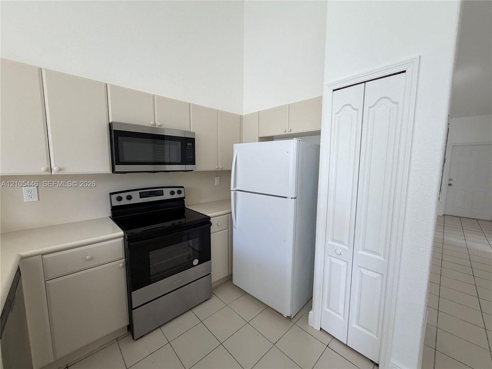 Kitchen featuring light cabinetry, a stainless steel microwave, and a black and stainless steel range