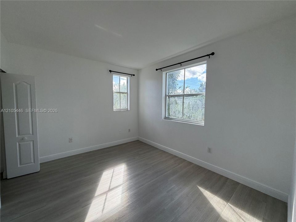 Light wood-finish flooring, white walls, and multiple windows