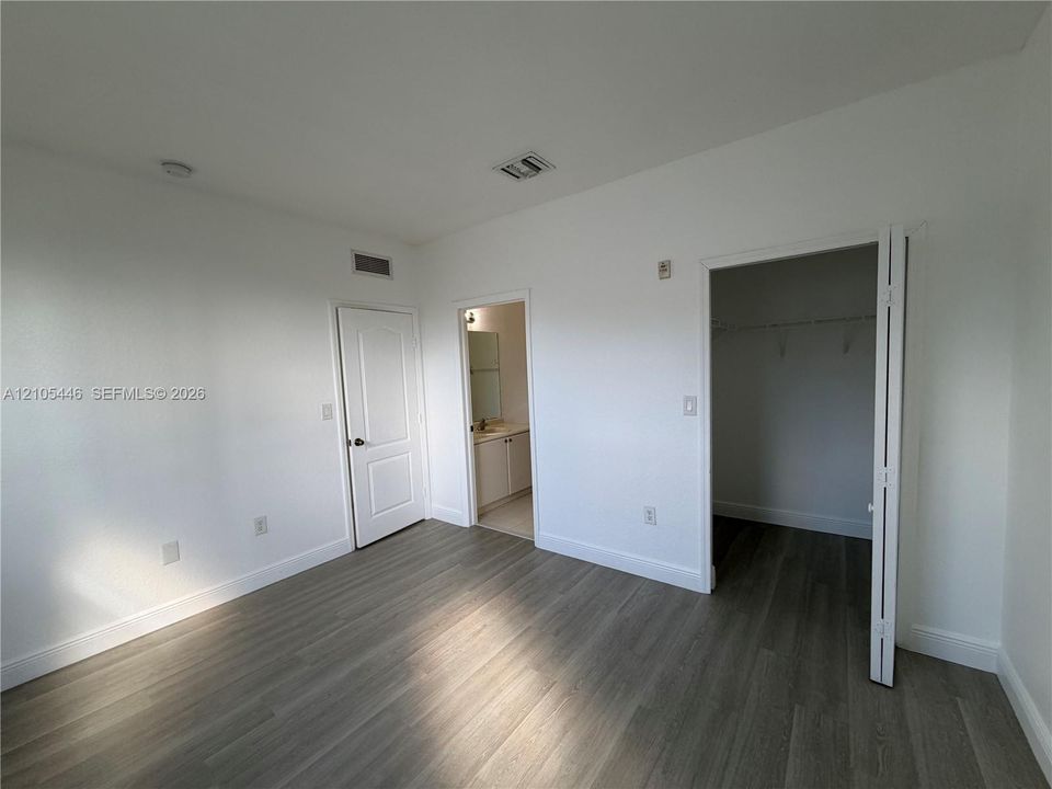 Wood-finish flooring, white walls, recessed ceiling lighting, and a closet with bifold doors