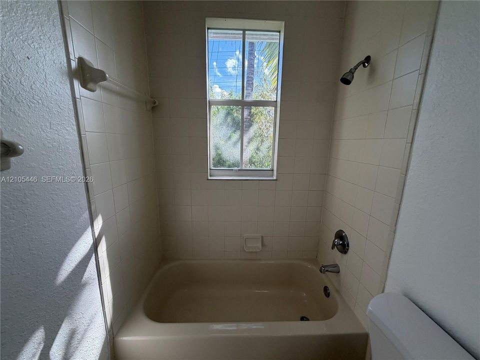 Bathtub with tile surround, a window, and chrome fixtures