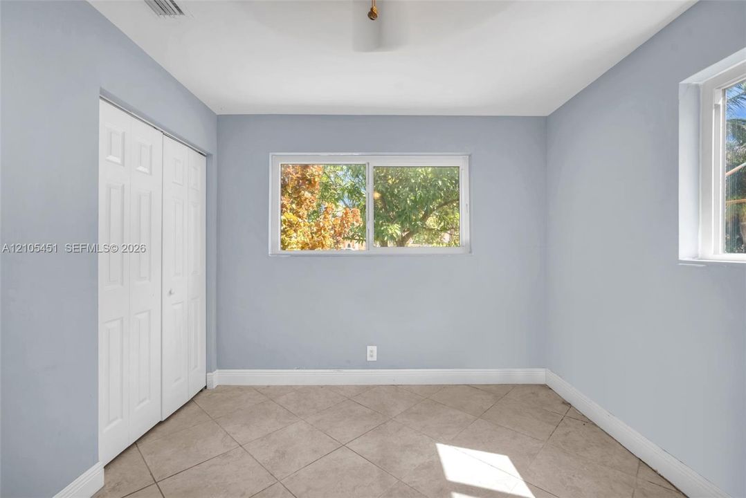 Interior space featuring light-toned neutral wall paint, tile flooring set on a diagonal pattern, white six-panel bi-fold closet doors, and horizontal sliding windows