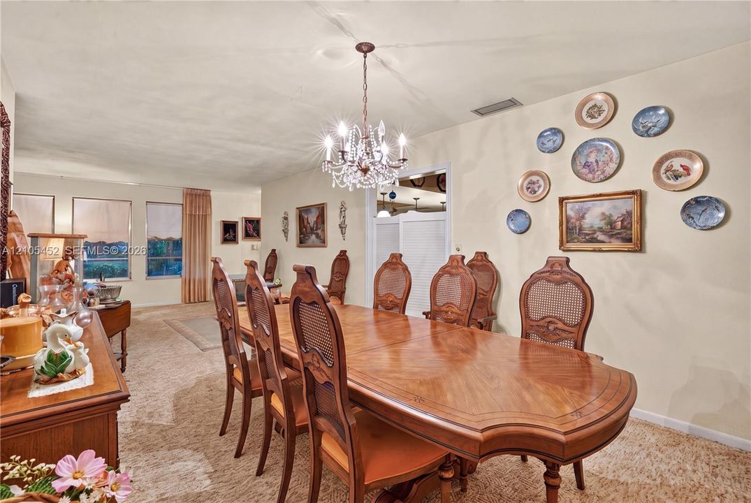 Dining area featuring high ceilings, a decorative crystal-style chandelier, neutral wall-to-wall carpeting, and large windows with integrated blinds