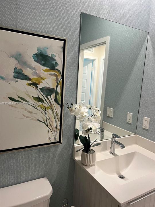 Vanity with integrated sink, polished chrome faucet, and expansive wall mirror