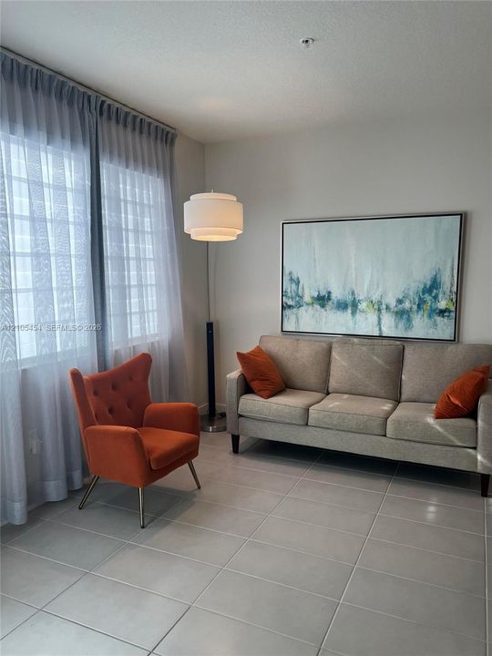 Tile flooring with light grout lines, ceiling-mounted light fixture, and floor-to-ceiling sheer curtains
