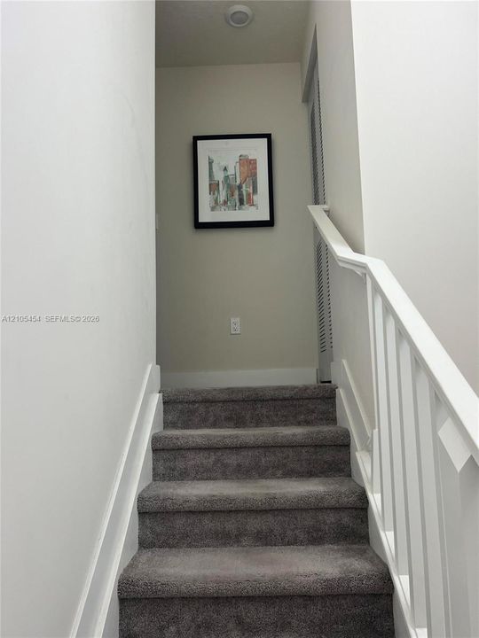 Staircase with gray carpeting and white handrails