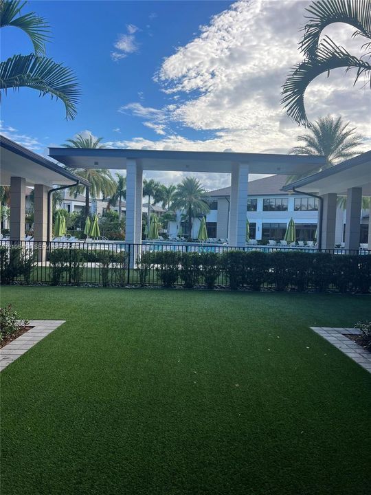Expansive artificial turf lawn with paver stone borders and surrounding shrubbery
