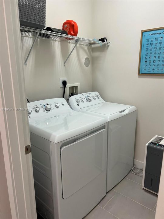 Laundry area featuring a wire storage shelf and light gray floor tiles