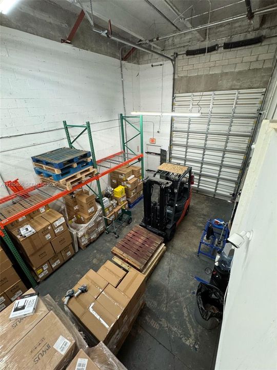 Industrial warehouse space featuring high ceilings, exposed masonry walls, durable concrete flooring, and a large overhead roll-up door
