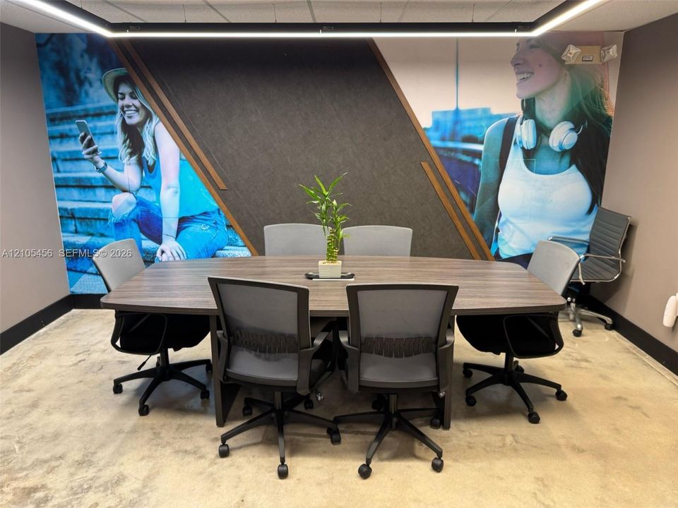 Conference room featuring a wood-finish table, polished concrete flooring, geometric wall paneling, and integrated linear overhead lighting