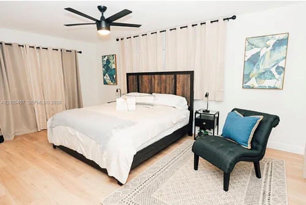 Light-toned wood-finish flooring and matte black ceiling fan with integrated lighting