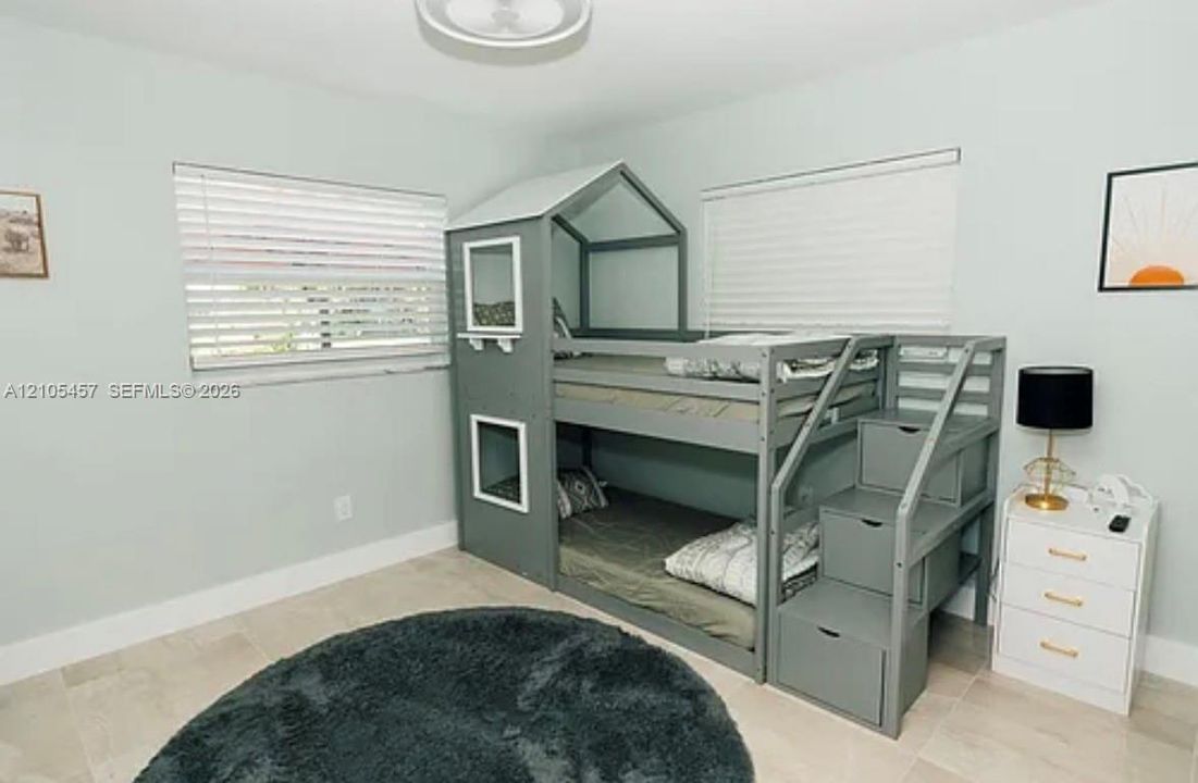 Neutral-toned tile flooring, dual windows with fitted horizontal blinds, and a central flush-mount light fixture