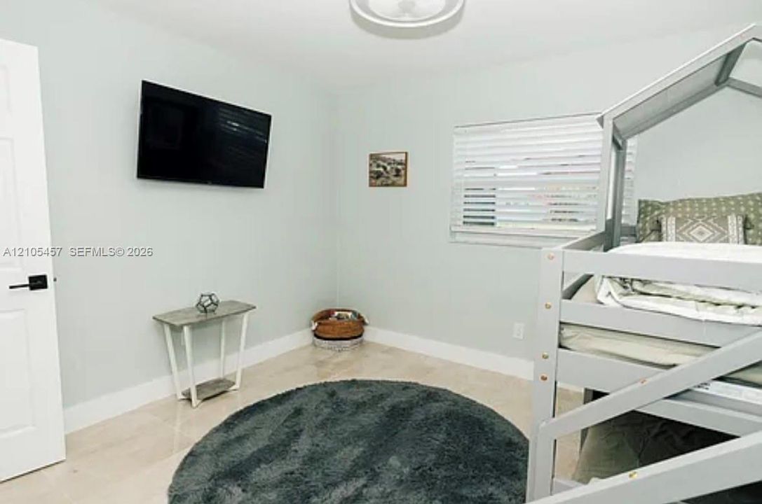 Neutral wall color, light-toned polished tile flooring, horizontal slat blinds, and a semi-flush mount ceiling fixture