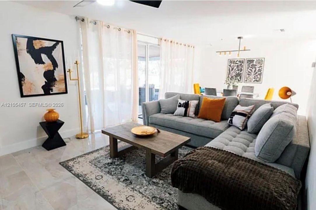 Large-format tile flooring, sliding glass doors, and linear multi-bulb chandelier