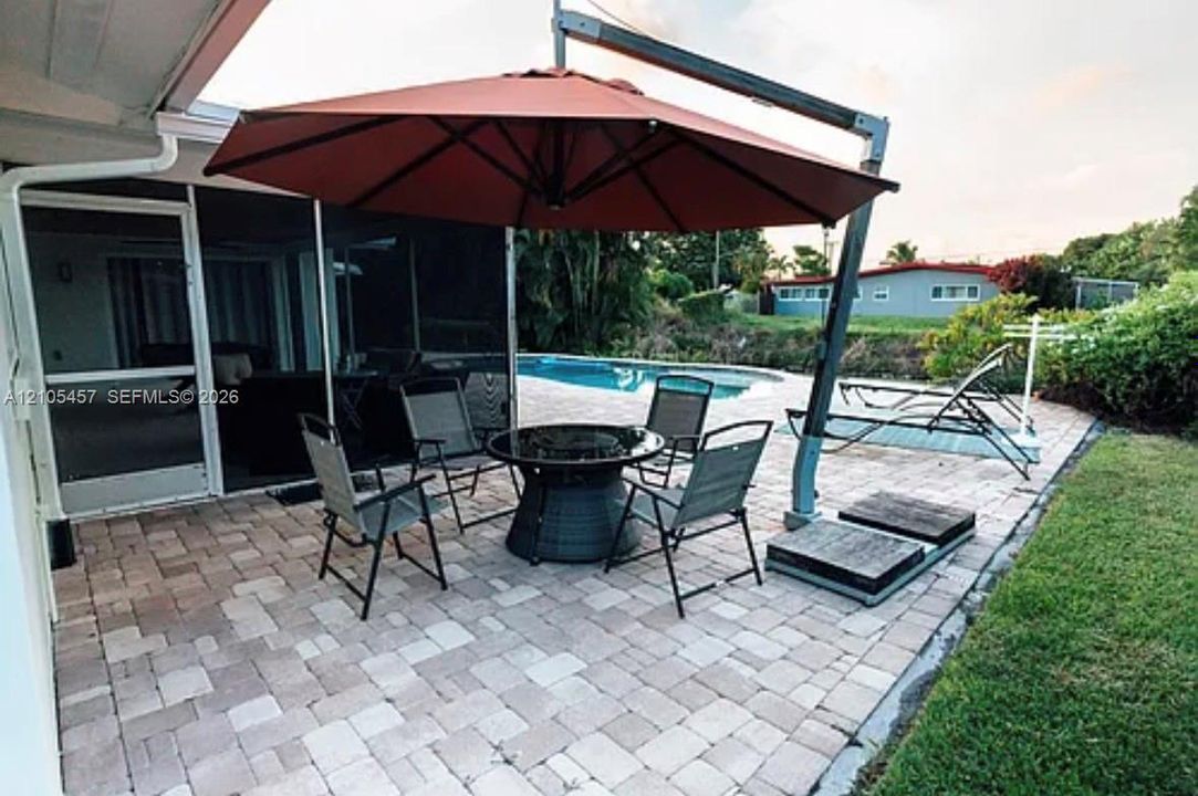 Paver patio featuring a screen-enclosed porch and a concrete swimming pool