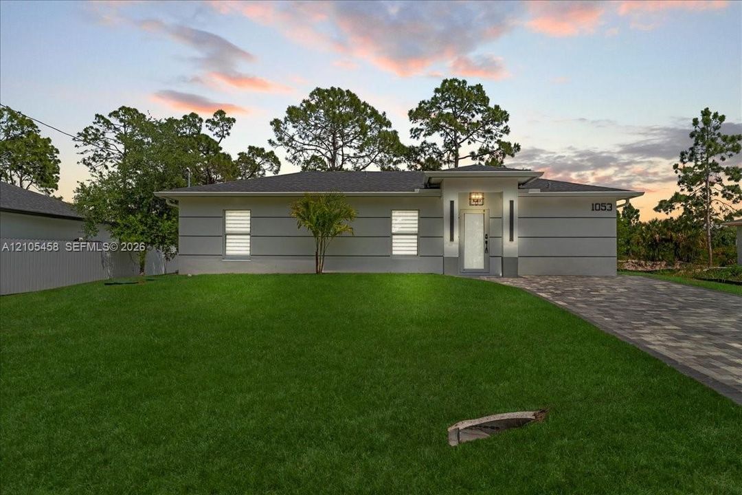 Modern exterior with horizontal siding, a paver driveway, and an established lawn