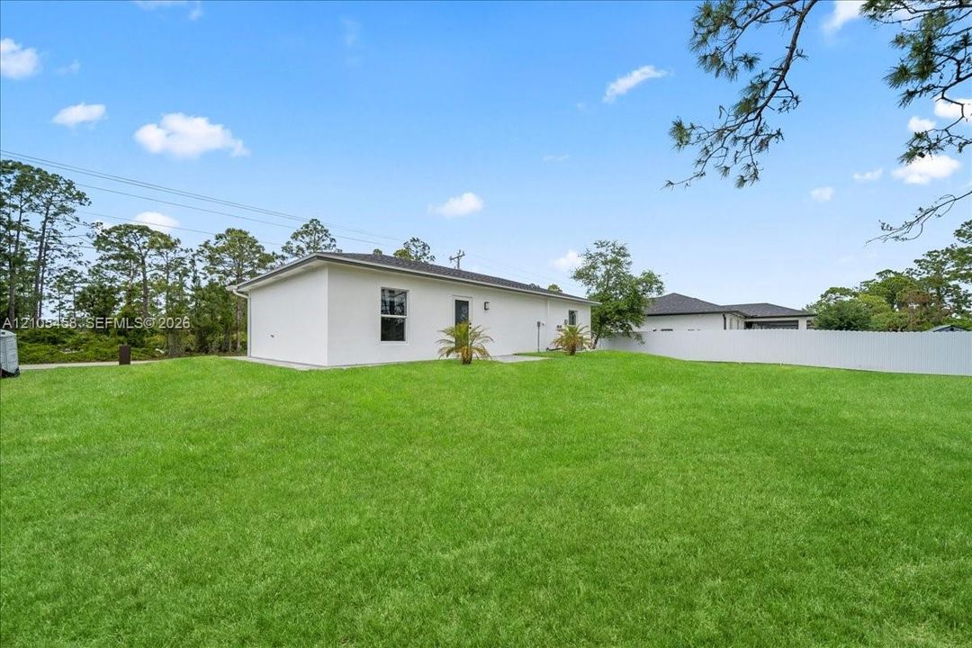 Expansive manicured lawn with mature landscaping and established trees, complemented by a modern white exterior featuring clean architectural lines and multiple windows