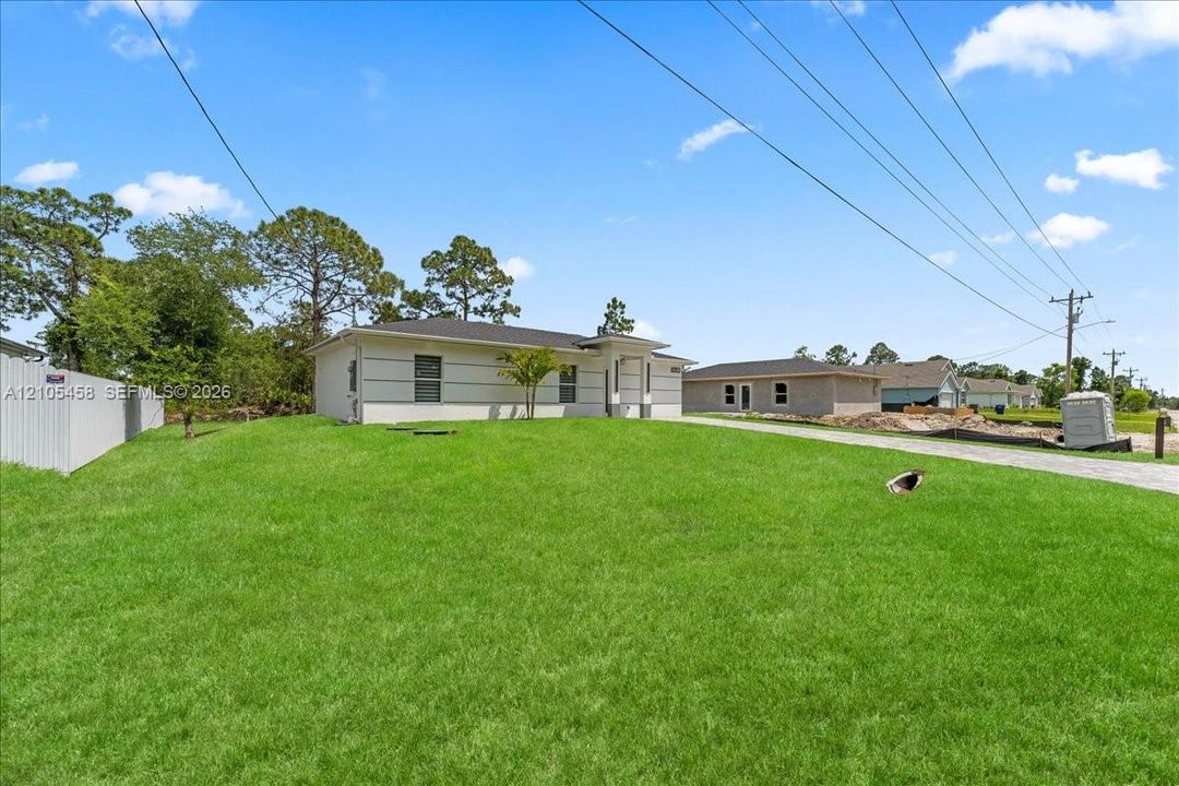 Manicured lawn, white privacy fence, and concrete driveway