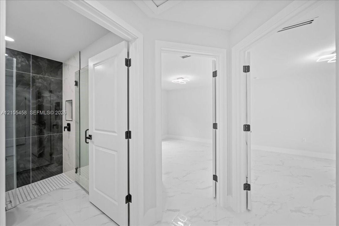 Walk-in shower with dark large-format tile, glass enclosure, and matte black fixtures