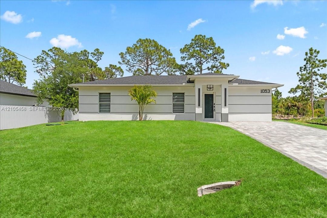 Contemporary-style exterior with a clean white and gray palette, dark entry door, and a paved driveway