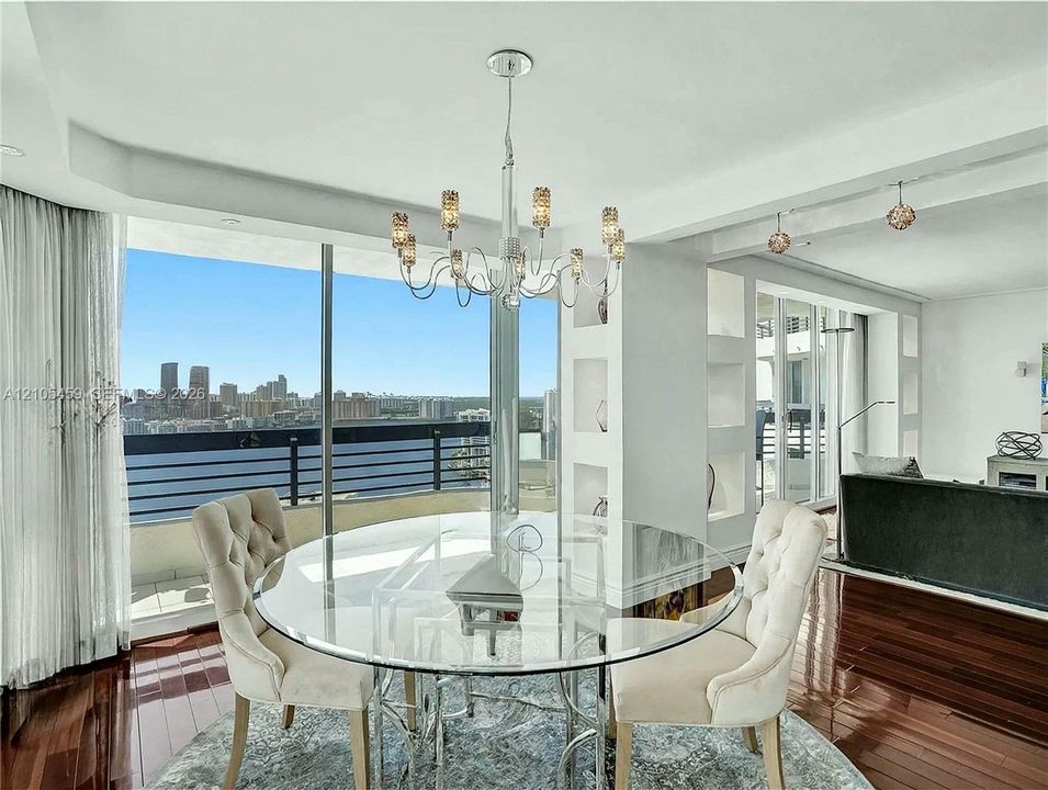 Expansive floor-to-ceiling windows, dark wood-finish flooring, recessed lighting, built-in shelving, and a modern chandelier