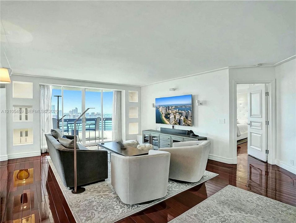 Rich wood-finish flooring throughout, integrated wall niches, and sliding glass doors opening to an outdoor living space