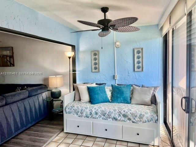 Enclosed patio space featuring a ceiling fan, tiled flooring, and sliding glass doors
