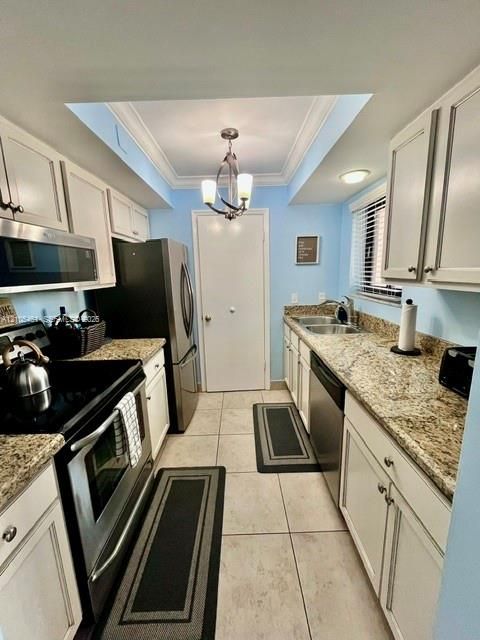 Galley kitchen featuring white cabinetry, stainless steel appliances, light-toned countertops, and recessed lighting