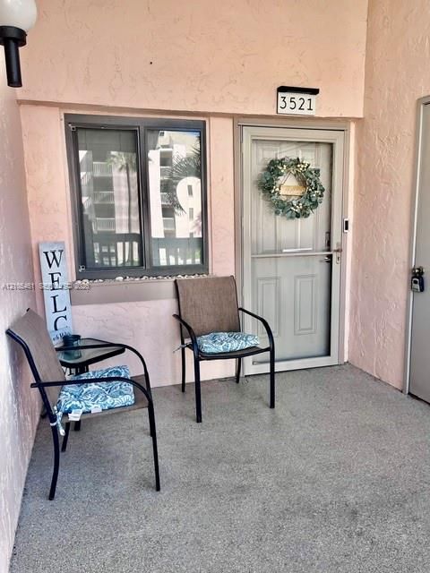 Textured exterior wall finish, exterior wall-mounted lighting, single-pane window, screened entry door, and concrete flooring