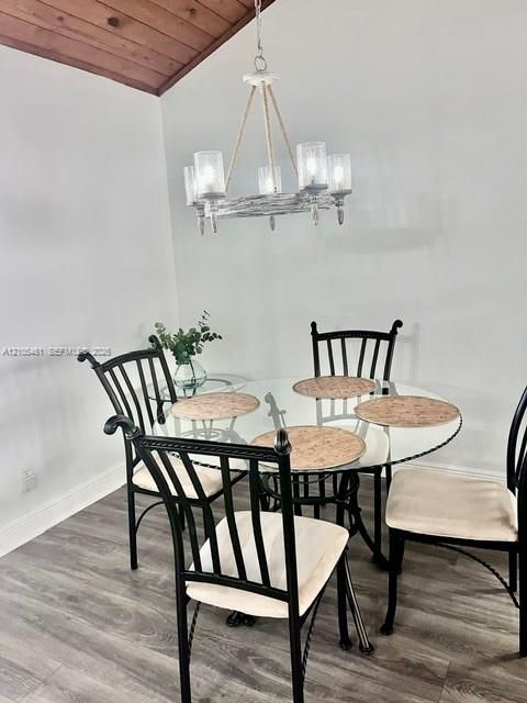 Vaulted wood-paneled ceiling, modern chandelier, light gray wood-finish flooring, and crisp white walls