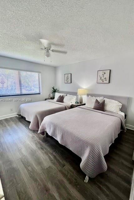 Wood-finish flooring with white baseboards, a window with horizontal blinds, and a ceiling fan