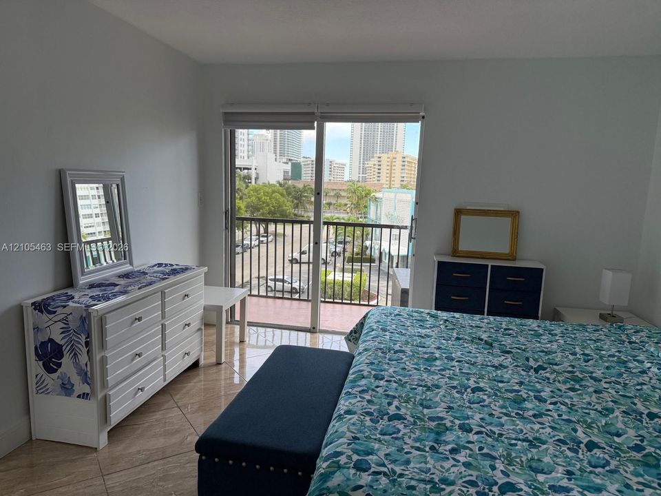 Slider door to balcony with metal railing, tile flooring, and city backdrop