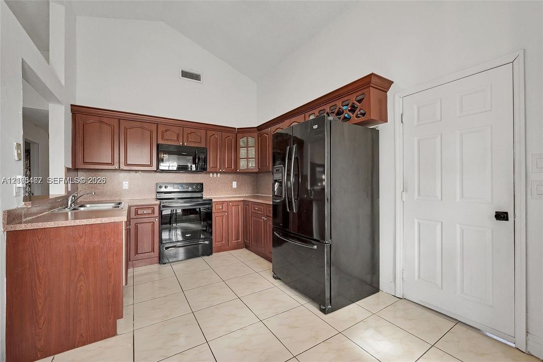Kitchen featuring wood cabinetry, integrated wine rack, high vaulted ceilings, and ceramic tile flooring