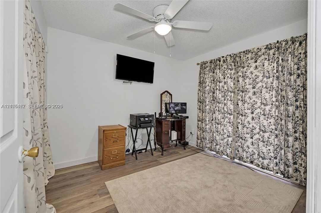 Room featuring wood-finish flooring and a central ceiling fan with an integrated light fixture
