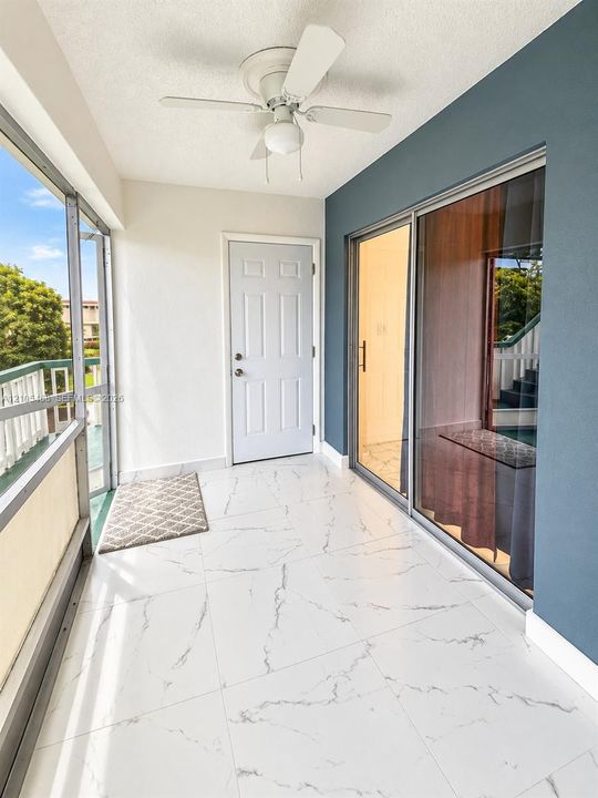 Enclosed balcony with white tile flooring, ceiling fan, and sliding glass door